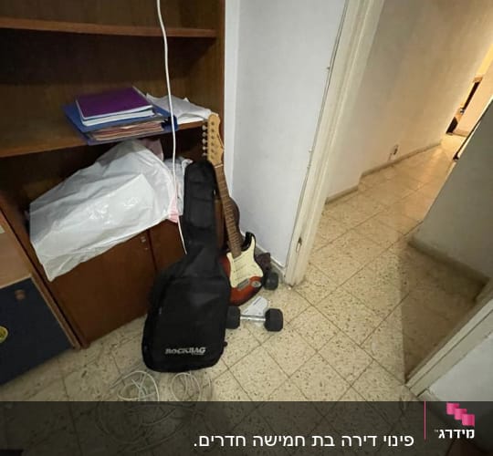 גיטרה חשמלית ותיק ליד מדף עם חוטים על הרצפה